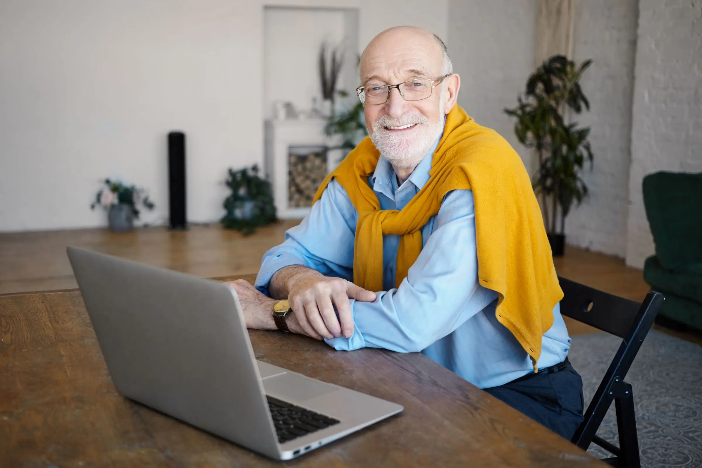 Older man working at laptop while smiling.