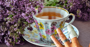 Picture of a fancy tea cup next to the author's bandaged hand.